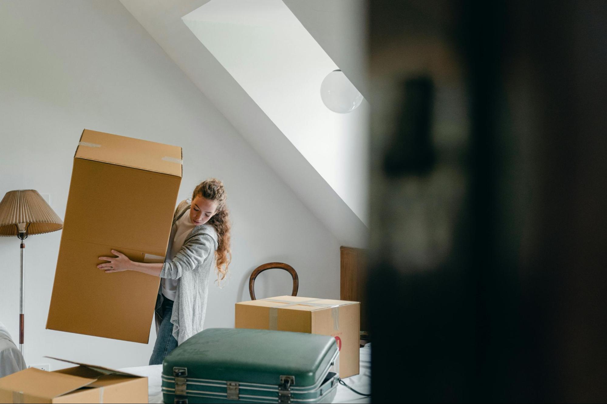 Picture of a person carrying boxes into a new home